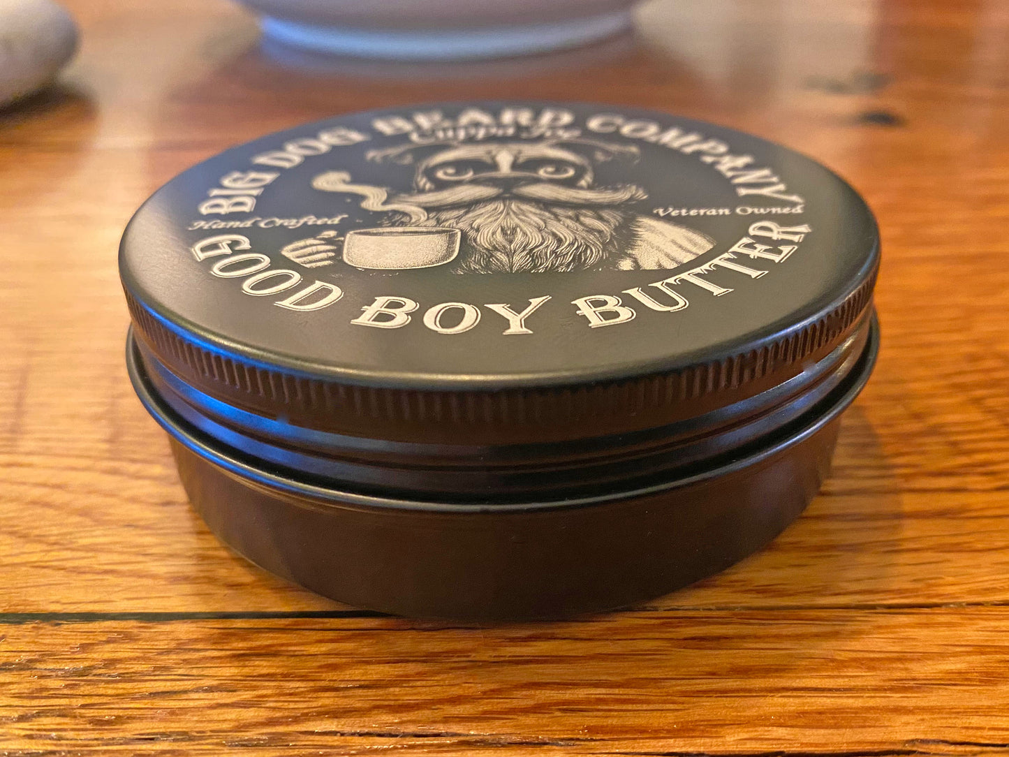 A tin of Cuppa Joe GOOD BOY Beard Butter by Big Dog Beard Company, closeup on table, front view