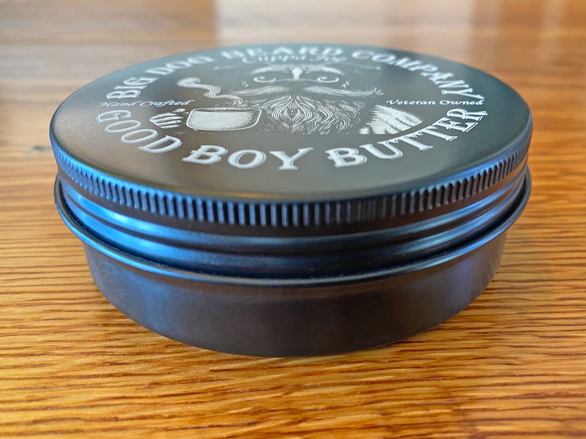 A tin of Cuppa Joe GOOD BOY Beard Butter by Big Dog Beard Company, closeup on table, front view